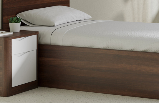 Table de chevet Acumen en bois foncé avec deux tiroirs blancs, intégrée dans une chambre de soins sécurisée