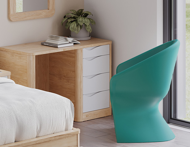 Bureau Acumen en bois clair avec tiroirs blancs et poignées intégrées, installé dans une chambre de soins avec fauteuil turquoise.