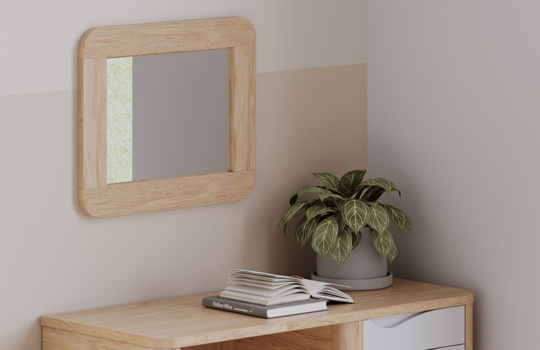 Miroir Acumen avec cadre en bois clair et finitions sécurisées, fixé au mur dans une chambre équipée de mobilier assorti.