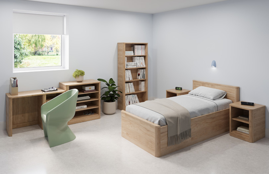 Chambre meublée gamme Acumen en bois clair avec lit simple, bureau, bibliothèque et tables de chevet ouvertes, conçue pour les environnements de soins